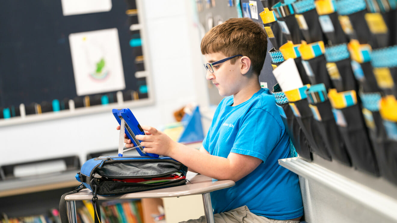 Boy sits in classroom on tablet