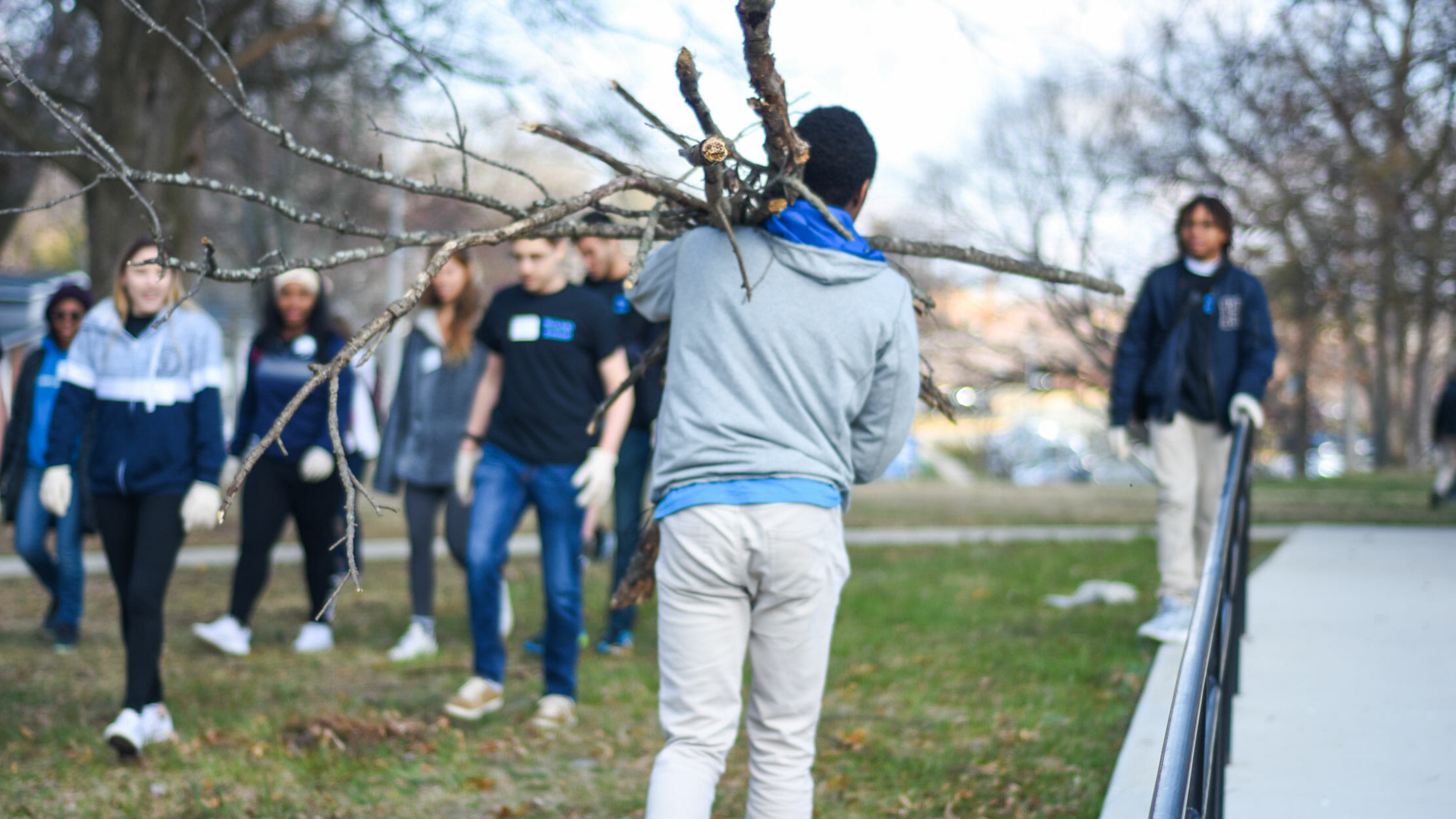 Student carries branches over shoulder