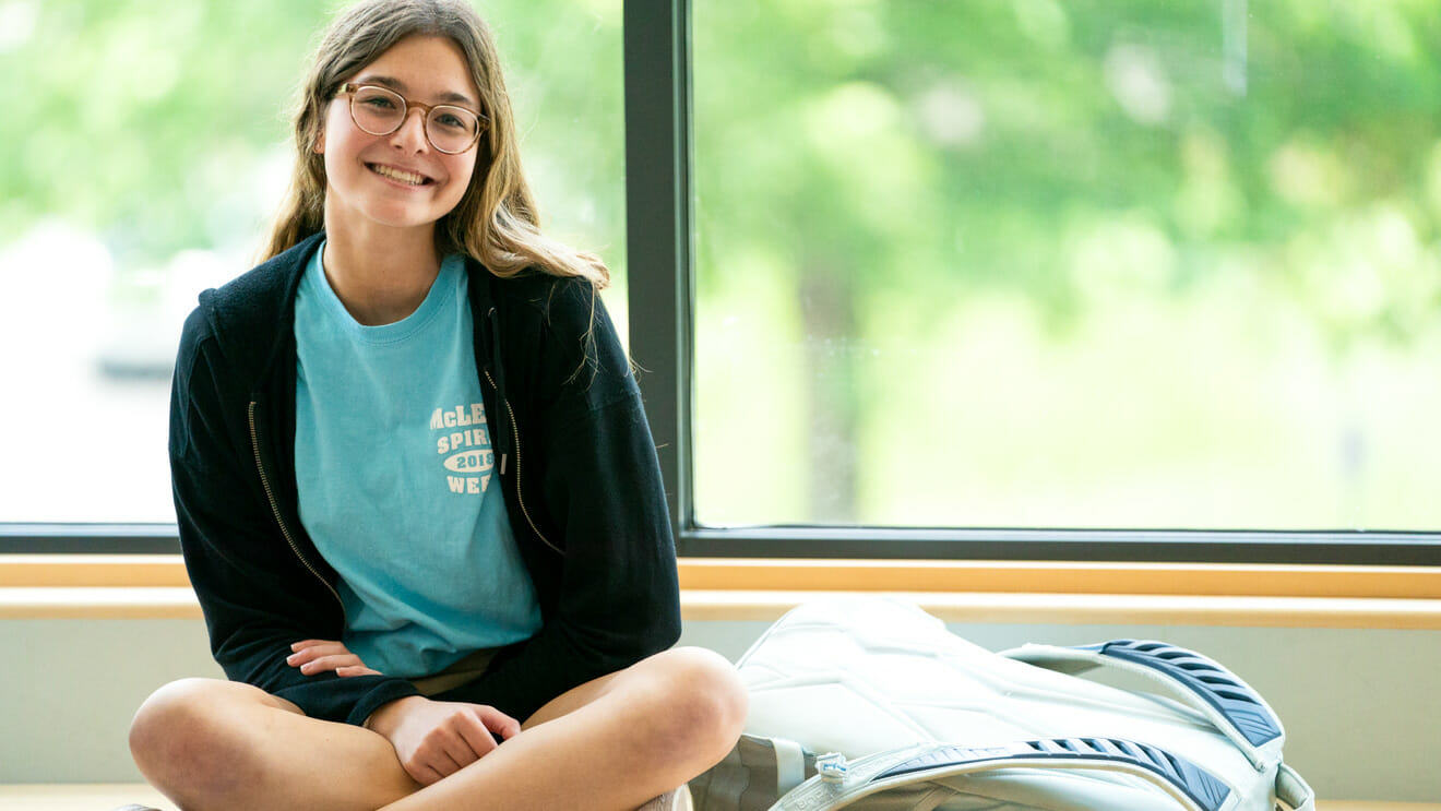 Smiling girl sits cross-legged in a windowsill