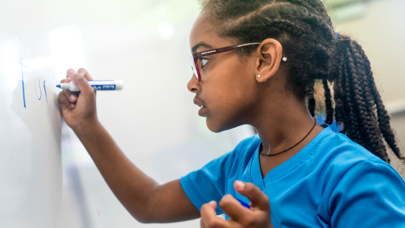 Girl writes on whiteboard in class