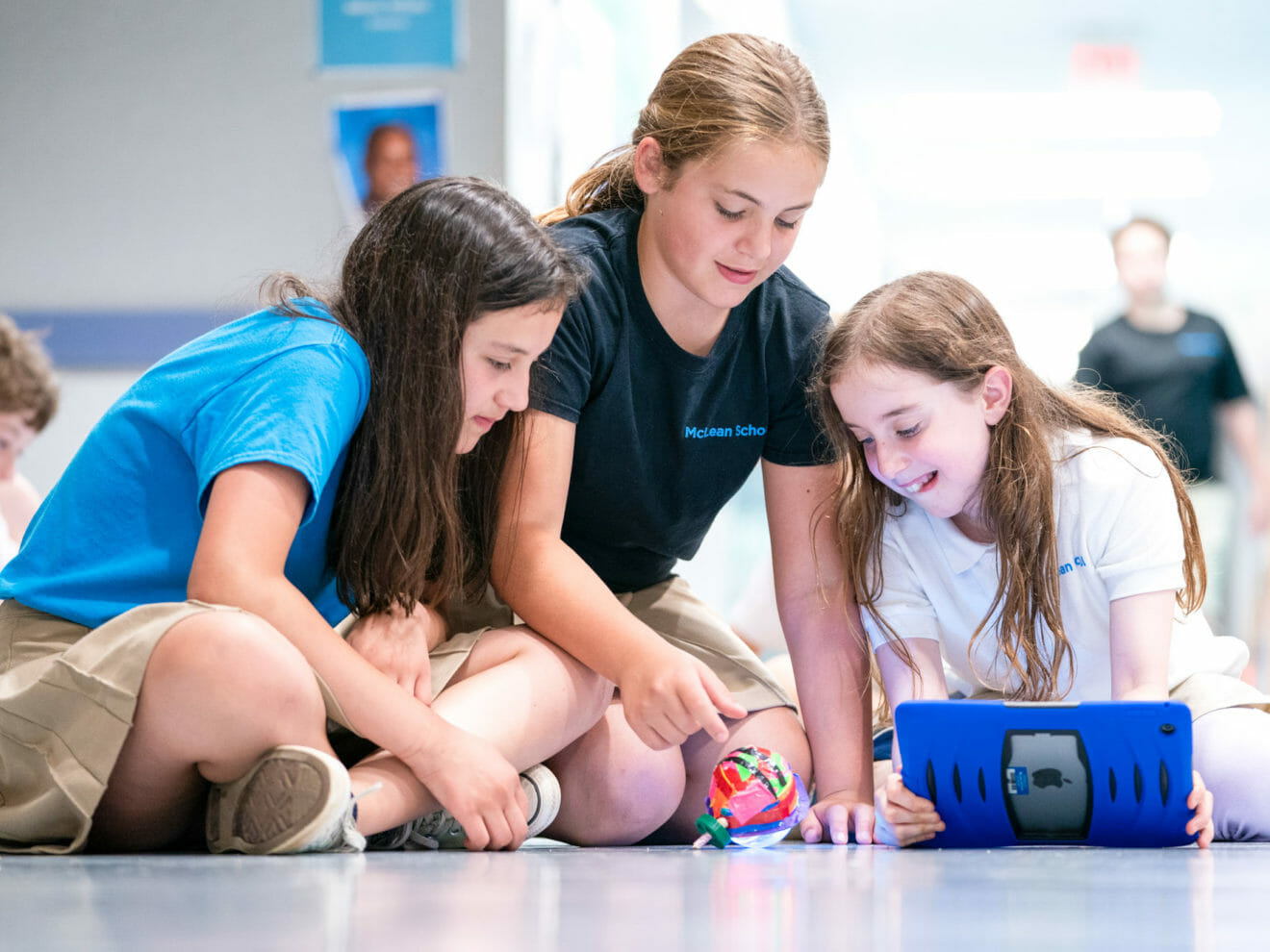 Three girls work on project in school hall