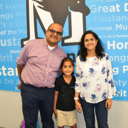 Parents and student stand in front of McLean School wall