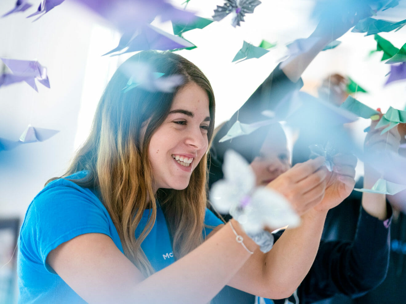 Smiling girl hangs origami birds