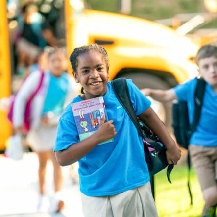 Smiling girl walks away from school bus