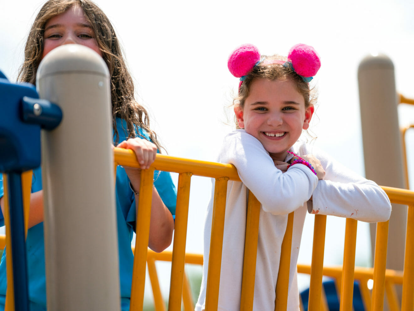 Smiling young girls stand on playground bridge