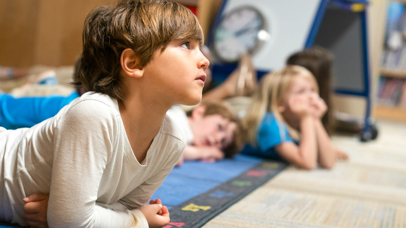 Young student lays on floor in class