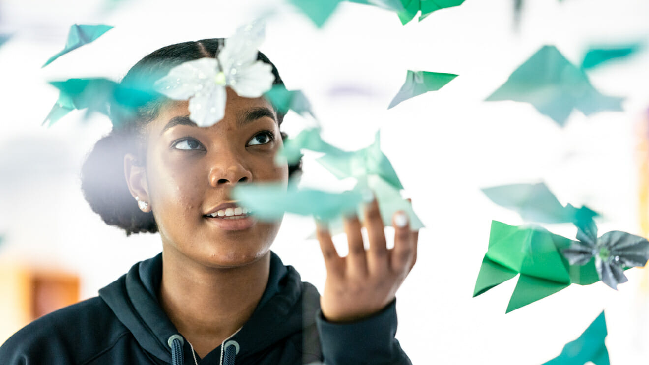 Smiling girl touches hanging origami birds