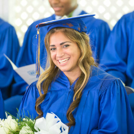 Smiling girl sits in row at graduation