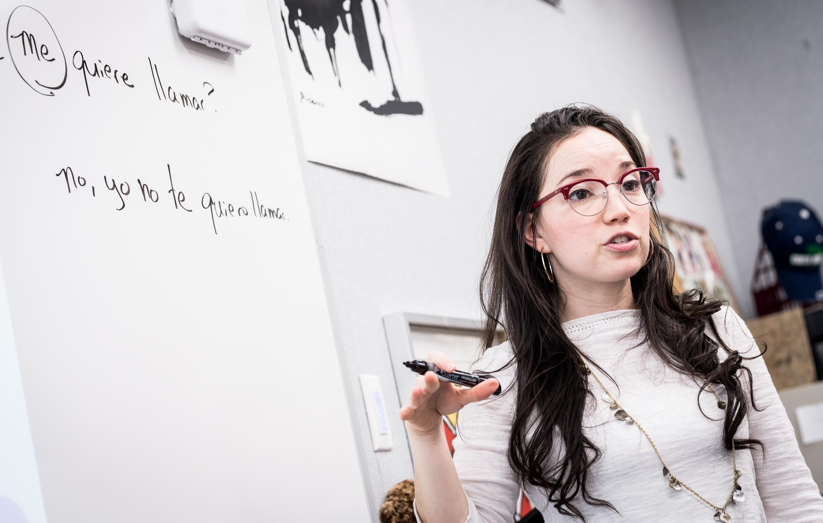 Upper school Spanish teacher stands near whiteboard