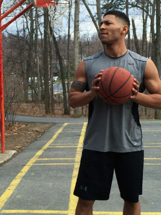 Emmanuel Joseph Mozo, Lower and Middle School Physical Education at McLean, poses with basketball on outside basketball court