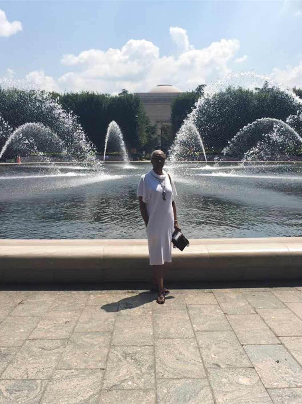 Sarah Smith, Upper School Administrative Assistant at McLean School, smiles at camera in front of a fountain