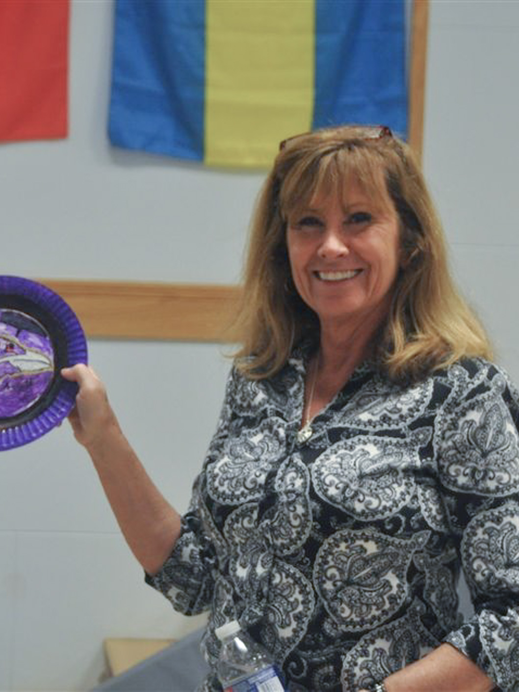 Marci Spilman, Grade 6 Teacher at McLean School, smiles while holding up her art