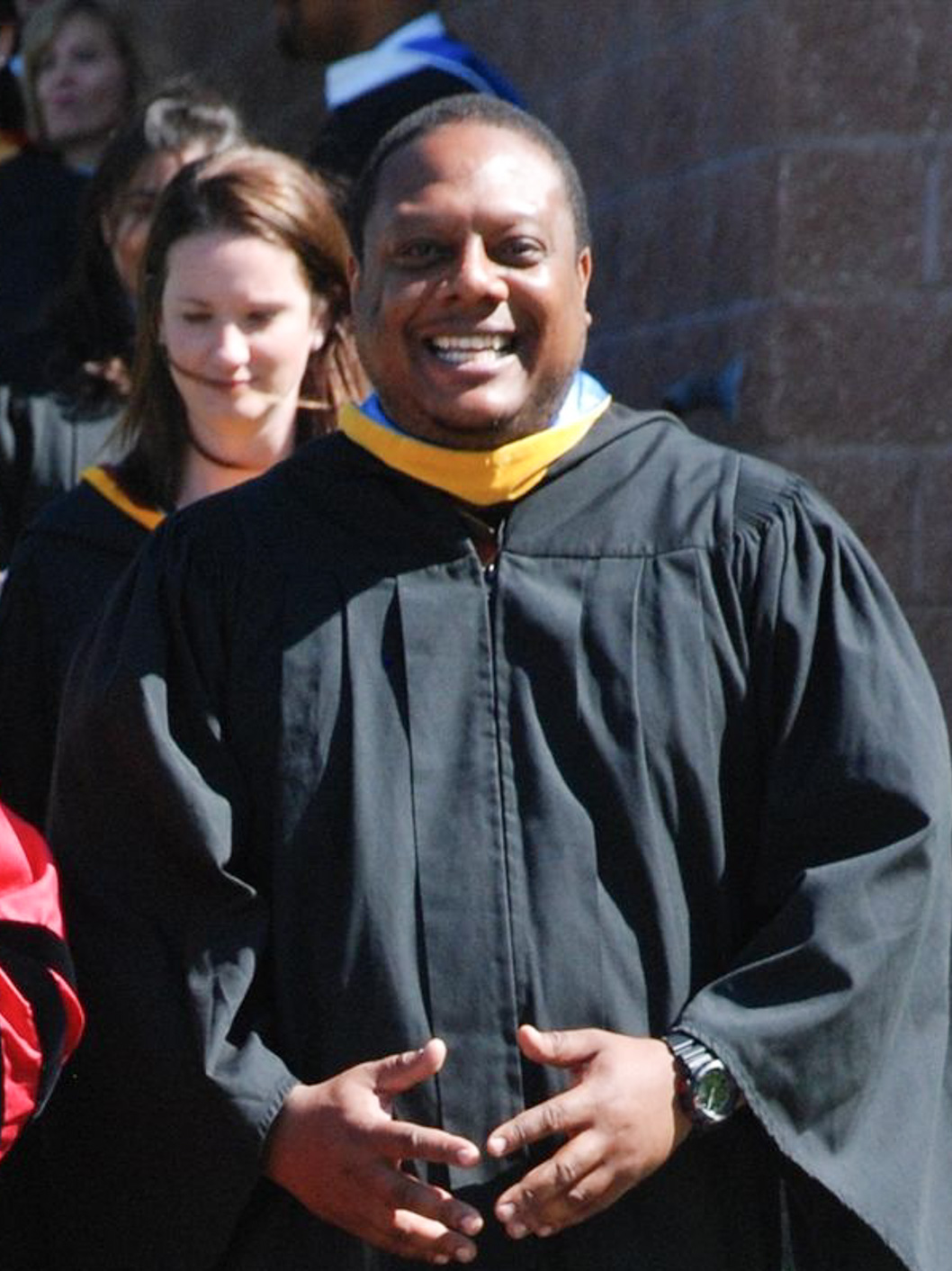 Nkosi White, Middle School Science Teacher at McLean School, smiles in graduation gown
