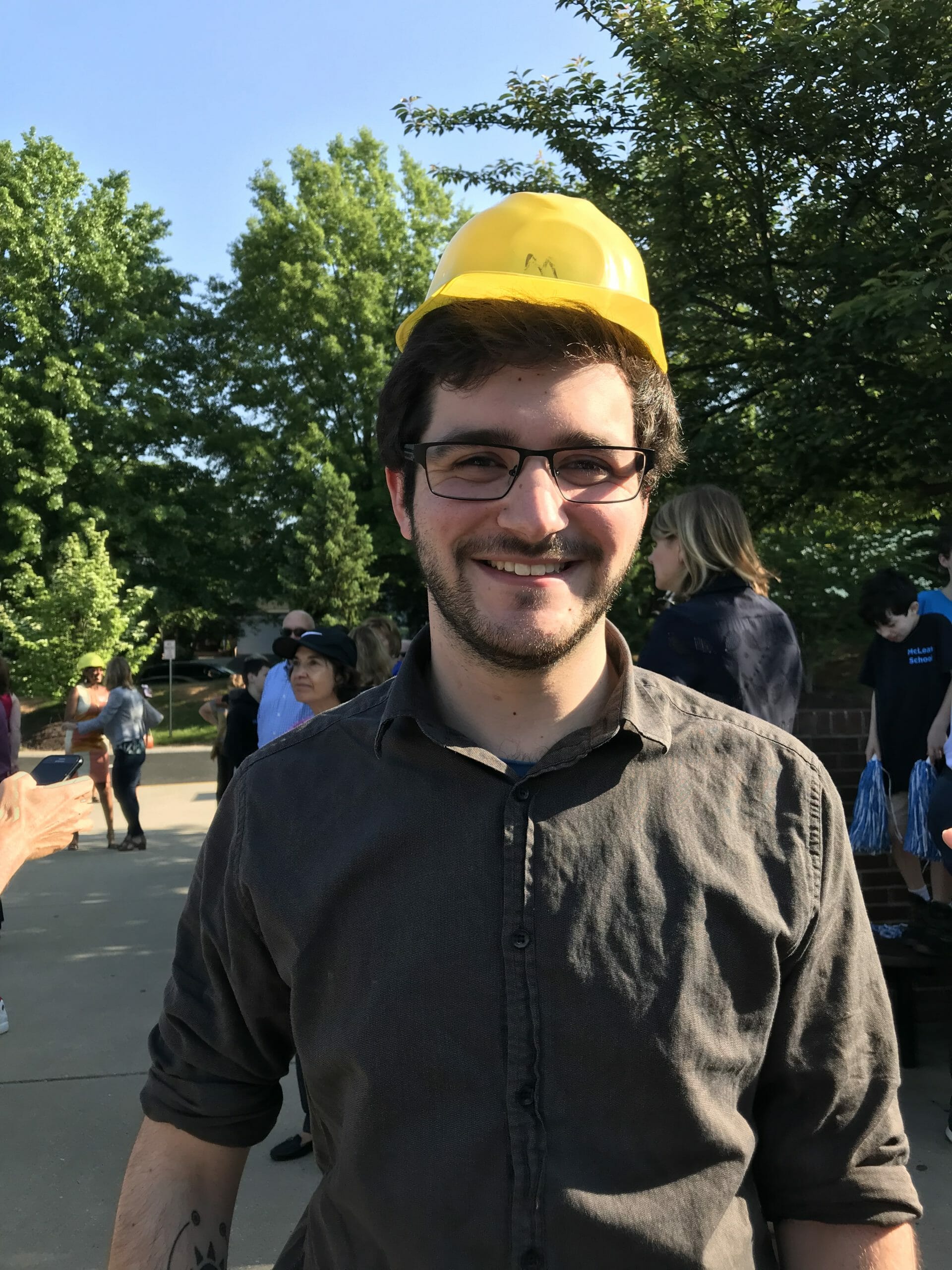 Jamie Tucker, Science Teacher at McLean School, smiles at camera with a yellow hardhat on
