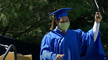 A student walking across the stage with his diploma.