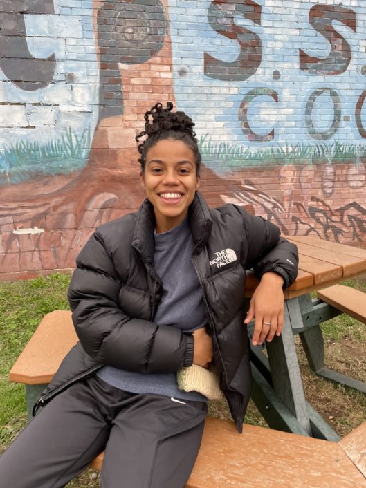 Amanda Flores, 1st grade teacher at McLean School, sitting on bench smiling at camera
