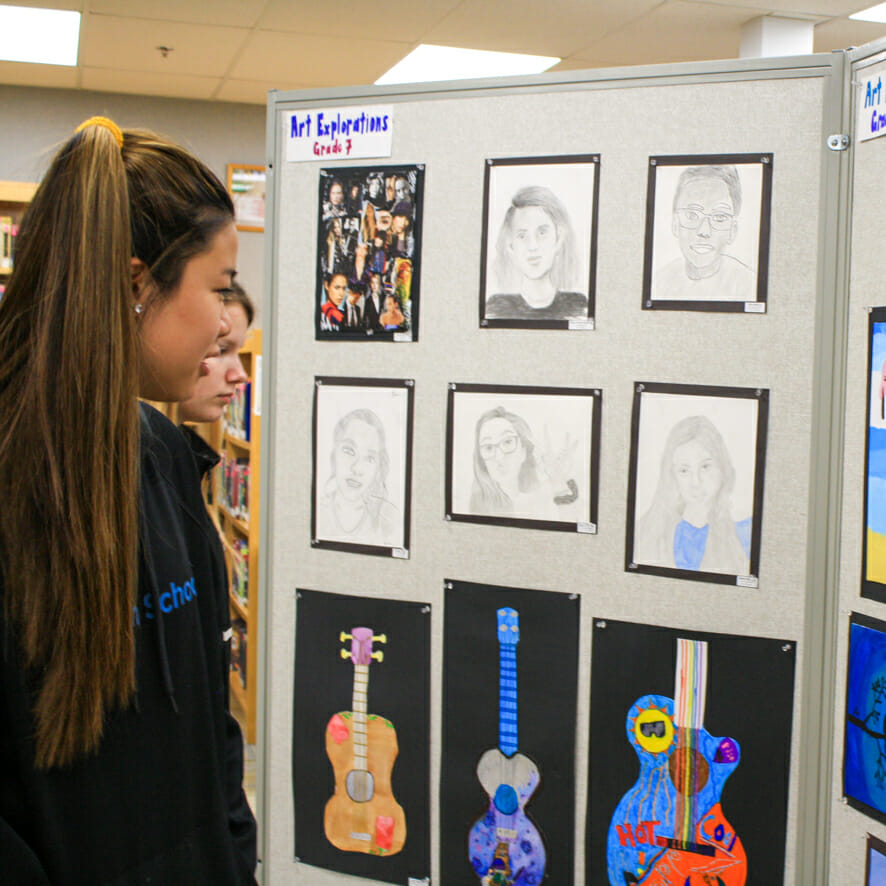 Students look at drawings in visual art show