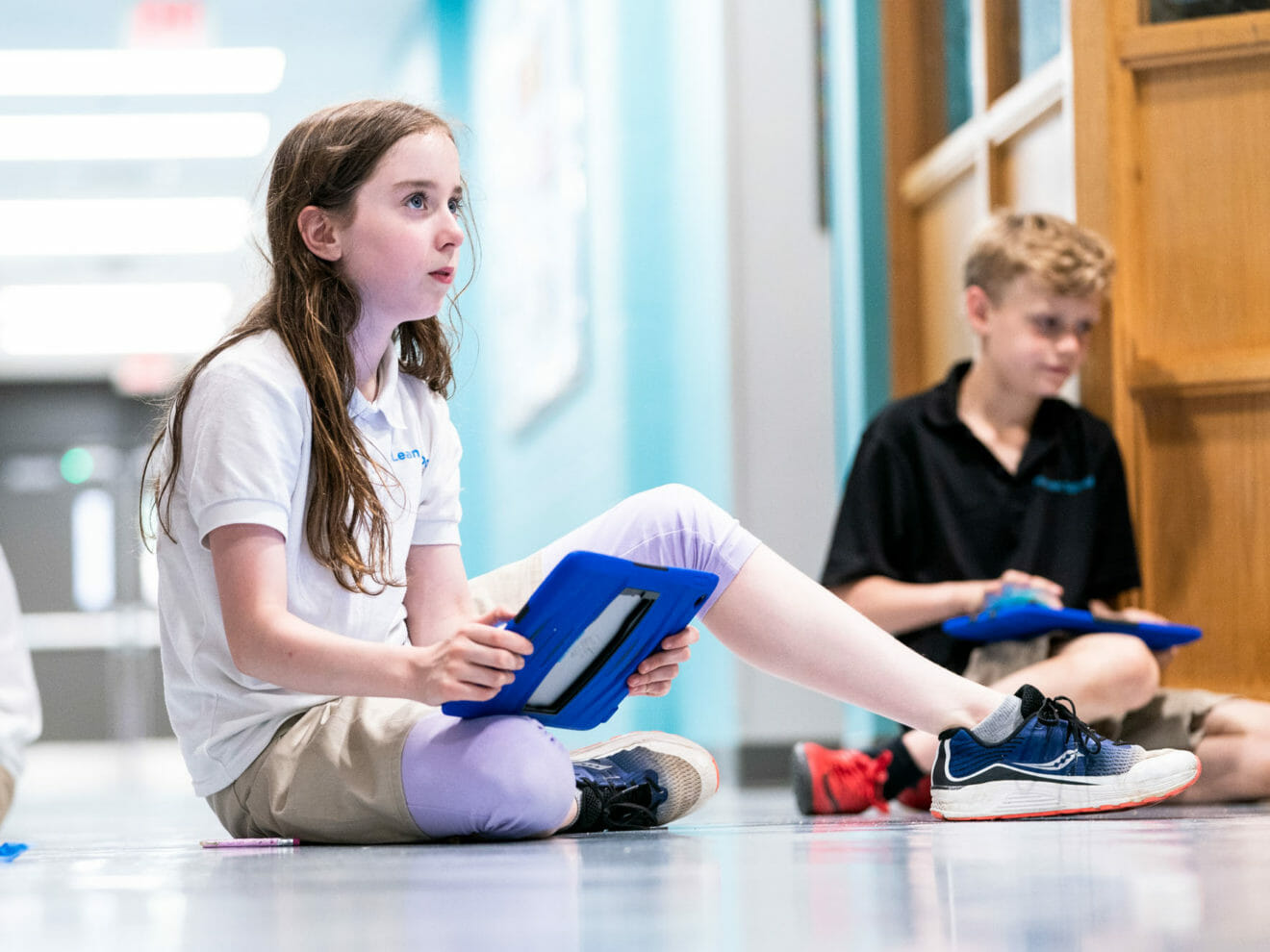 Girl uses iPad for project in school hallway