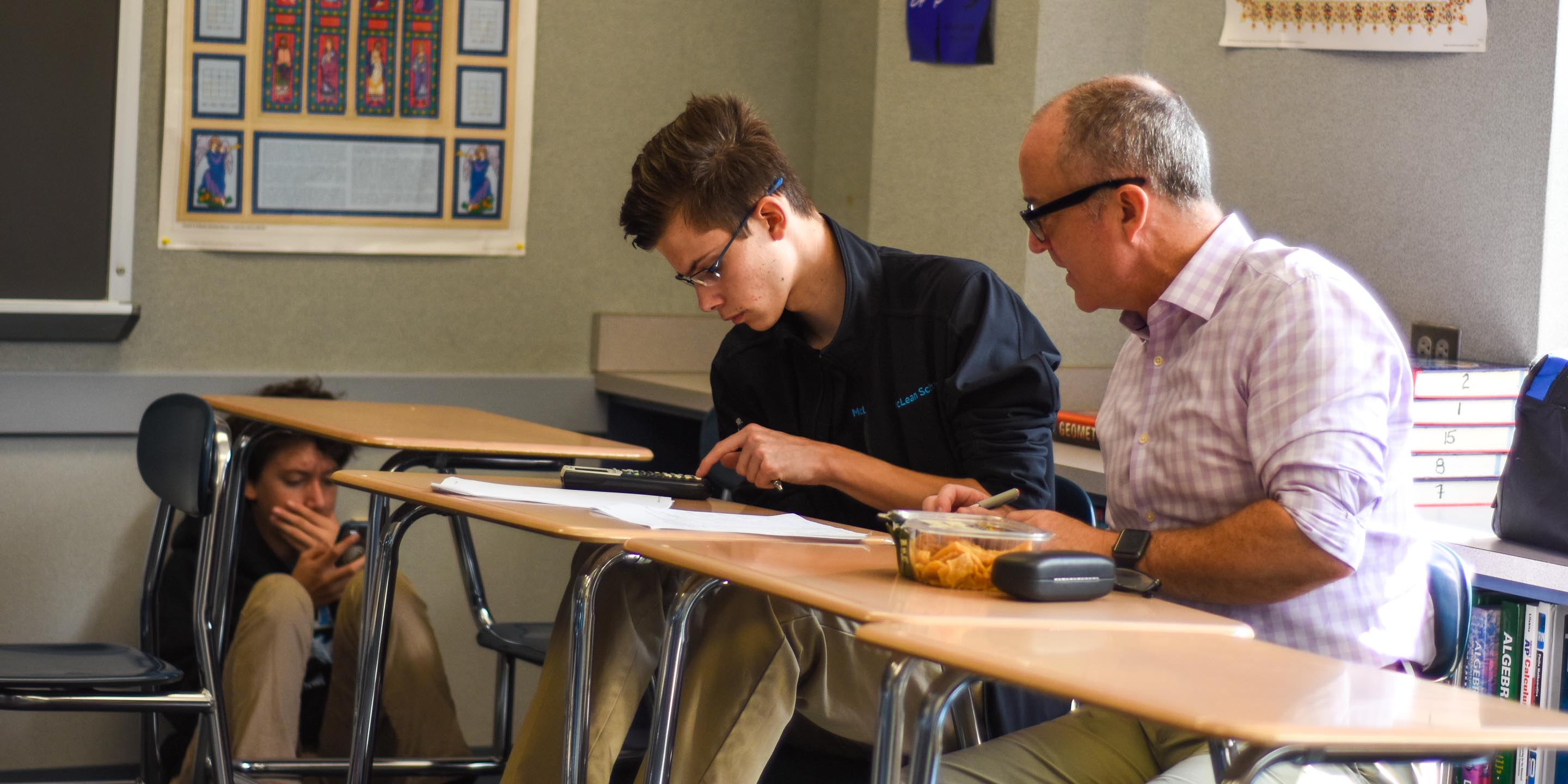 Student and teacher work on math at desk together