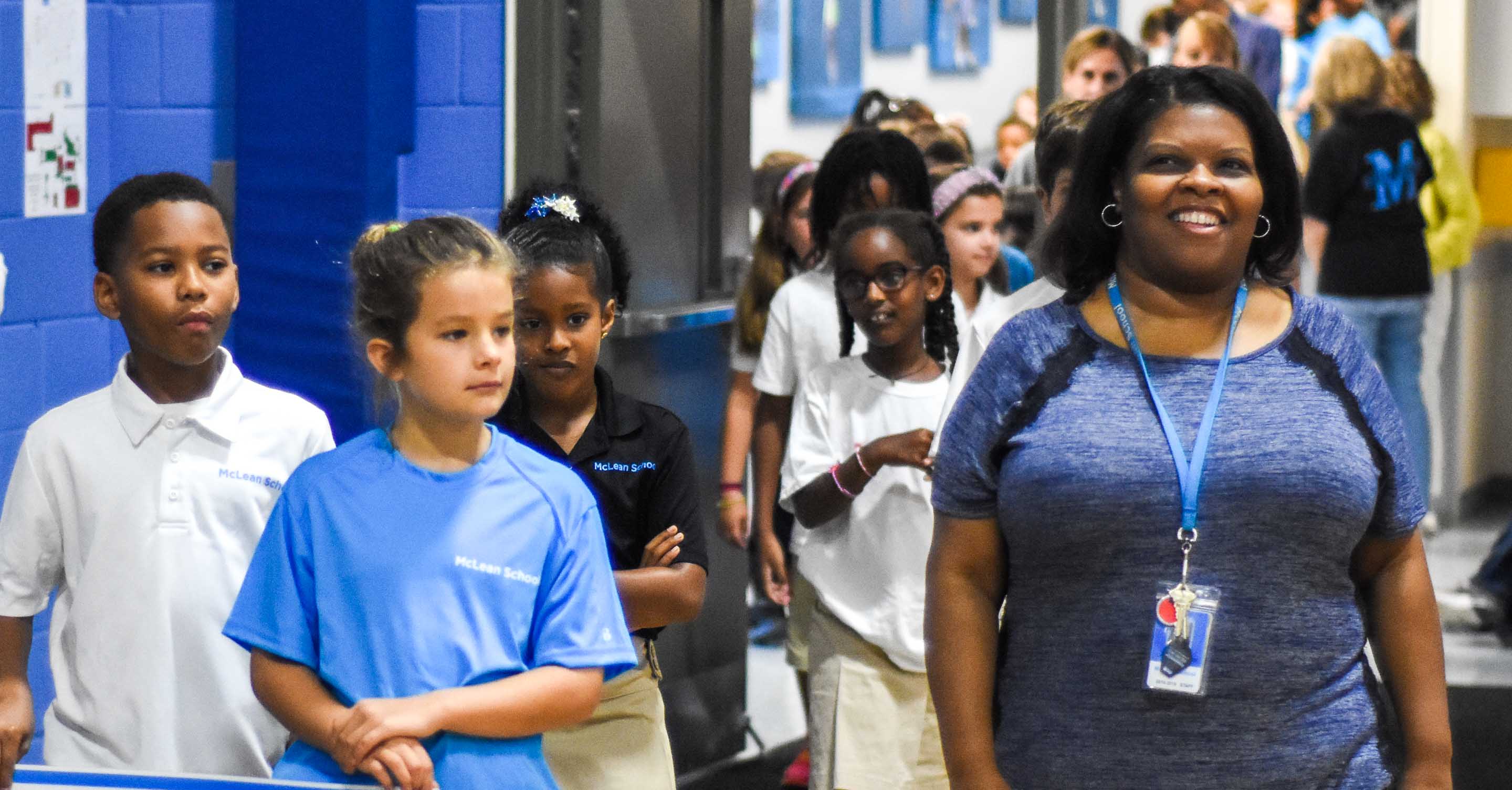 Teacher and students walk into school assembly