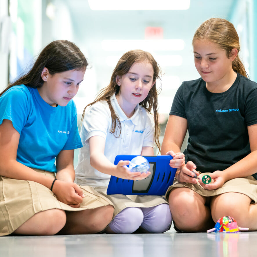 Three students work on project in school hallway