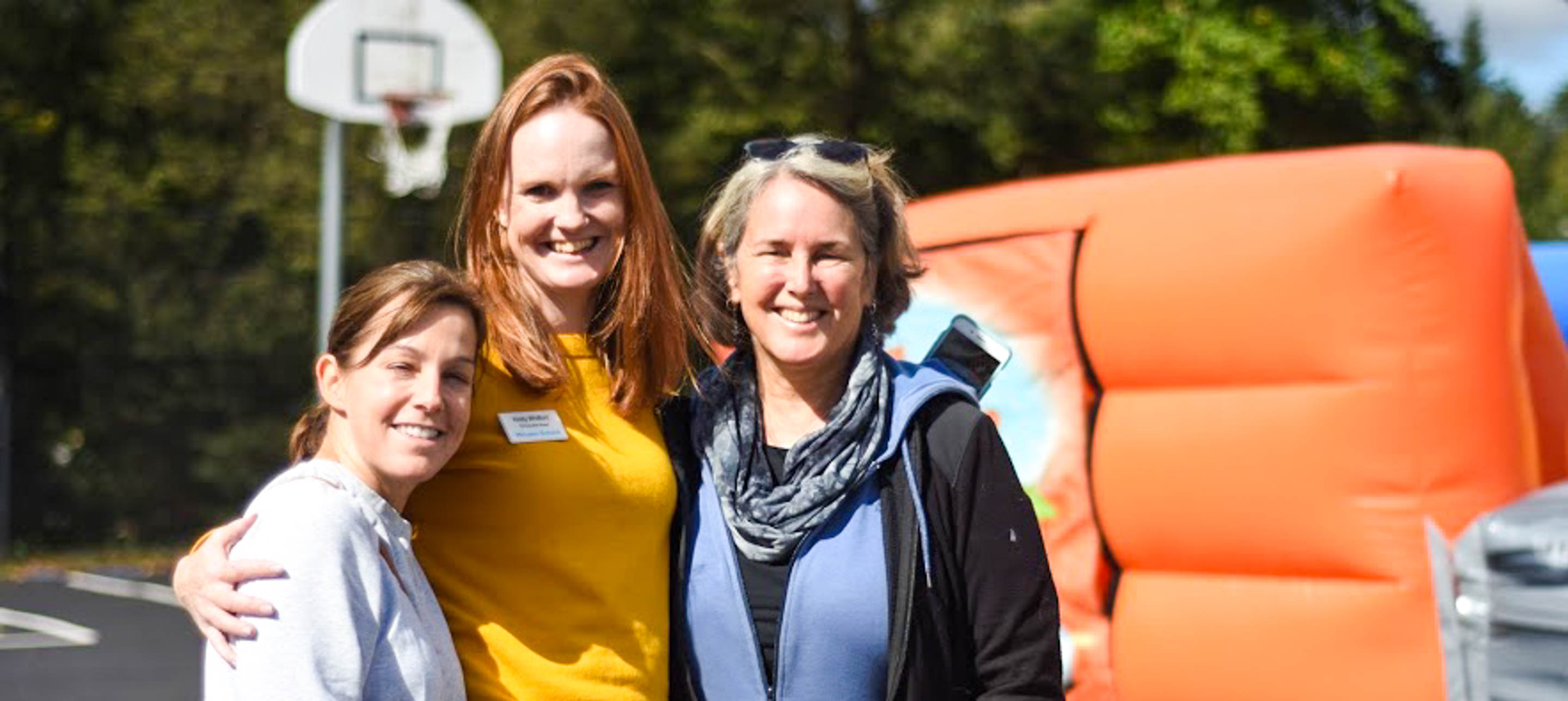 Three women stand outside on basketball court