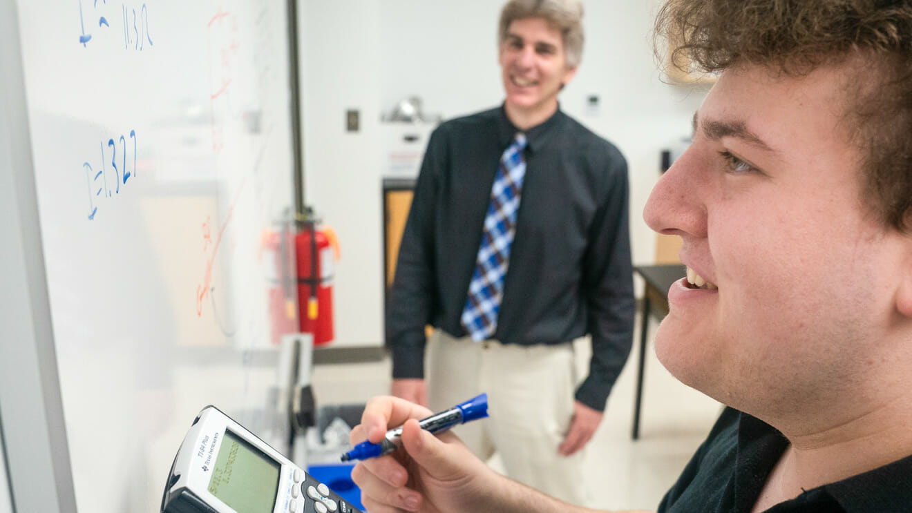 Upper school student writes on whiteboard