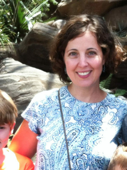 Sarah Baxter, a Math Specialist at McLean, smiling with her arms around two kids
