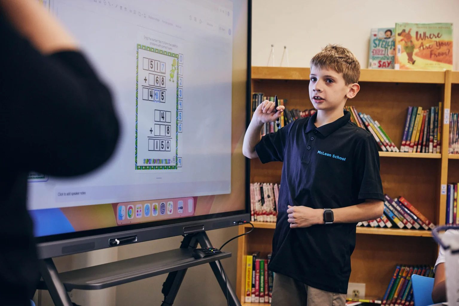 A boy standing in front of a large screen.