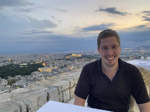 A man sitting at a table with a city in the background.